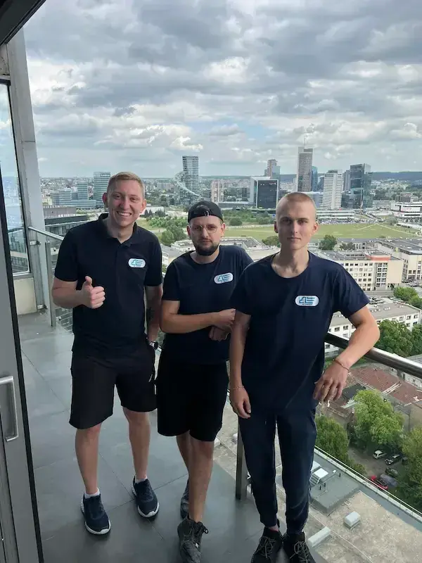 Three movers in navy uniforms on a high-rise balcony above the city